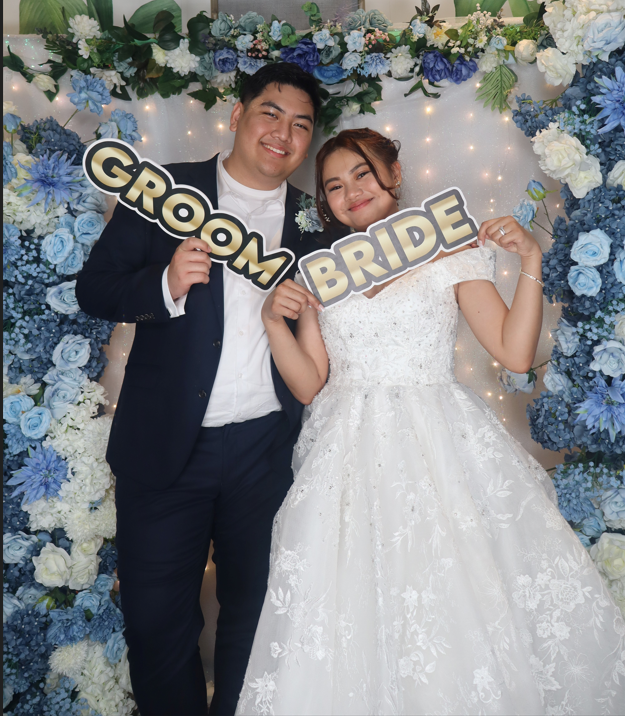 Open air photobooth bride and groom portrait with blue floral backdrop